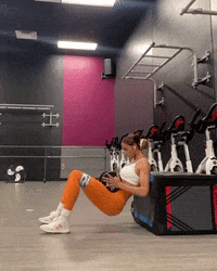 A Woman Sitting On A Box In A Gym GIF
