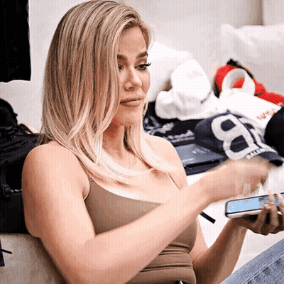 A Woman Sitting On A Couch Holding A Cell Phone With The Number 8 On It GIF