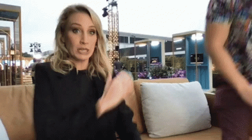 A Woman Sitting On A Couch Talking To Another Person GIF