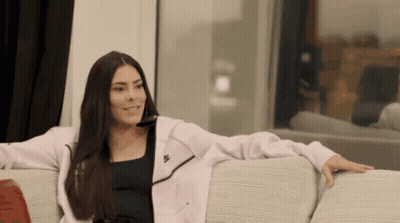 A Woman Sitting On A Couch Wearing A Nike Jacket GIF