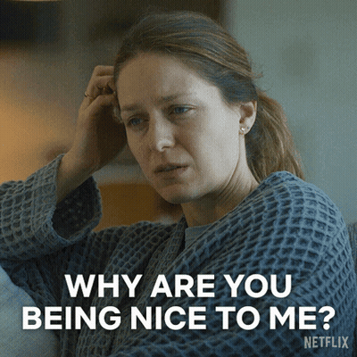 A Woman Sitting On A Couch With A Caption That Says Why Are You Being Nice To Me Netflix GIF