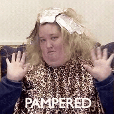 A Woman Sitting On A Couch With Pampered Written On The Bottom Of Her Face GIF