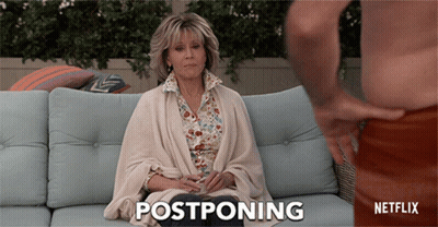 A Woman Sitting On A Couch With The Word Postponing Written On The Bottom GIF