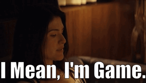 A Woman Sitting On A Couch With The Words " I Mean I 'M Game " Behind Her GIF