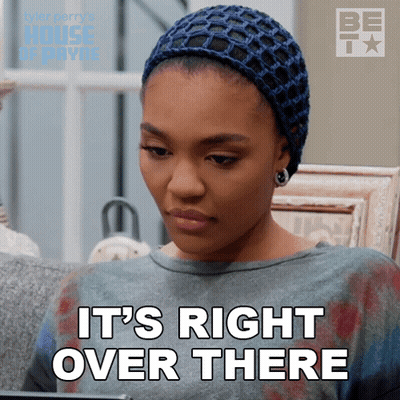 A Woman Sitting On A Couch With The Words " It 'S Right Over There " On Her Face GIF