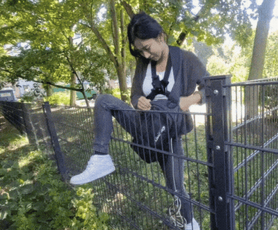 A Woman Sitting On A Fence With A Bag That Says Reebok GIF