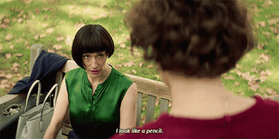 A Woman Sitting On A Park Bench Talking To Another Woman Who Says " I Look Like A Pencil " GIF