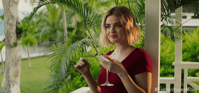 A Woman Sitting On A Porch Holding A Martini Glass GIF