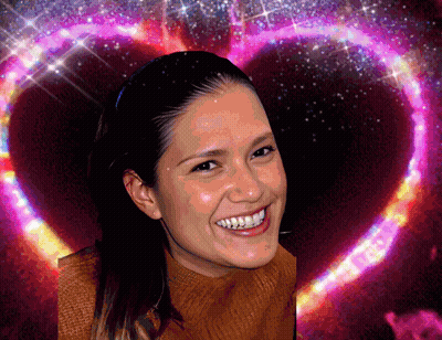 A Woman Smiles In Front Of A Heart Shaped Background GIF