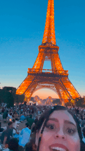 A Woman Smiles In Front Of The Eiffel Tower At Night GIF