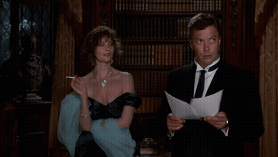 A Woman Smoking A Cigarette Next To A Man Reading A Letter GIF
