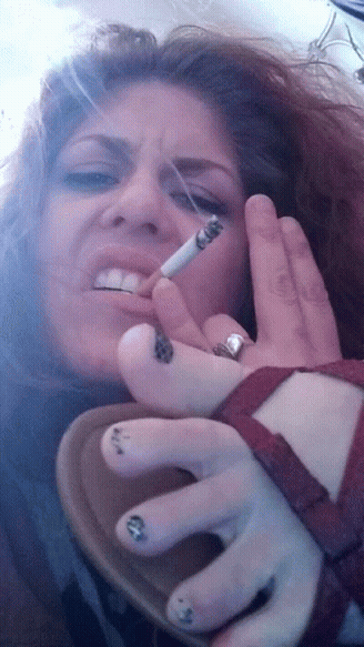A Woman Smoking A Cigarette With A Ring On Her Left Hand GIF
