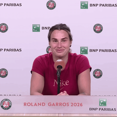 A Woman Speaking Into A Microphone In Front Of A Roland Garros Banner GIF