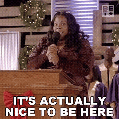 A Woman Speaking Into A Microphone With The Words " It 'S Actually Nice To Be Here " Below Her GIF