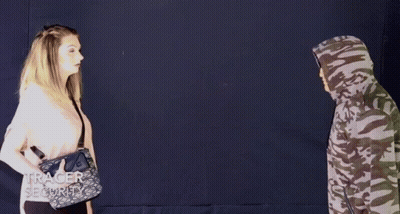 A Woman Spraying A Man With A Purse That Says Tracer Security On It GIF