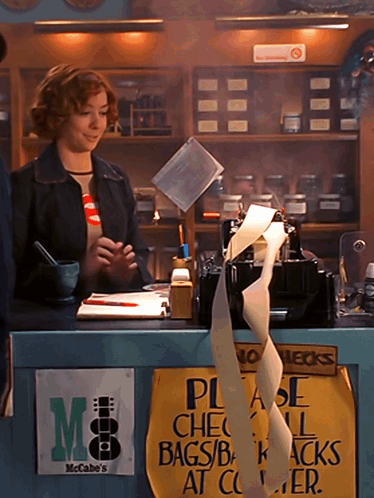Woman Behind Counter With Please Check Bags Sign GIF