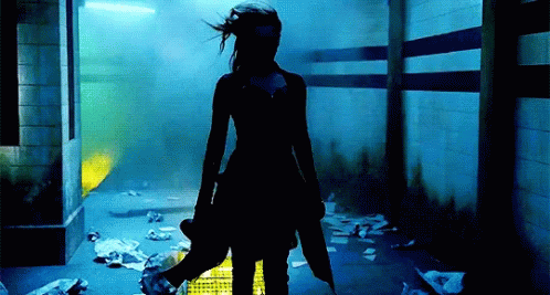 A Woman Standing In A Dark Room Holding A Puppet GIF