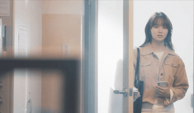 A Woman Standing In A Doorway Holding A Phone GIF