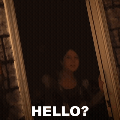 A Woman Standing In A Doorway With The Words Hello Written On The Bottom GIF