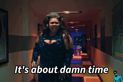 A Woman Standing In A Hallway With The Words It 'S About Damn Time GIF