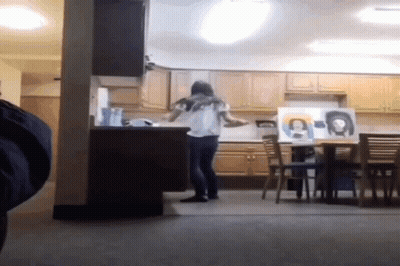 A Woman Standing In A Kitchen With A Painting Of A Woman On The Wall GIF