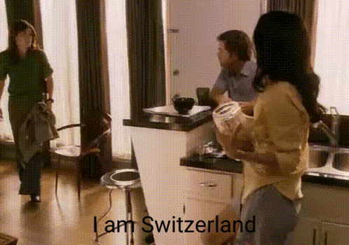 A Woman Standing In A Kitchen With The Words I Am Switzerland On The Bottom GIF