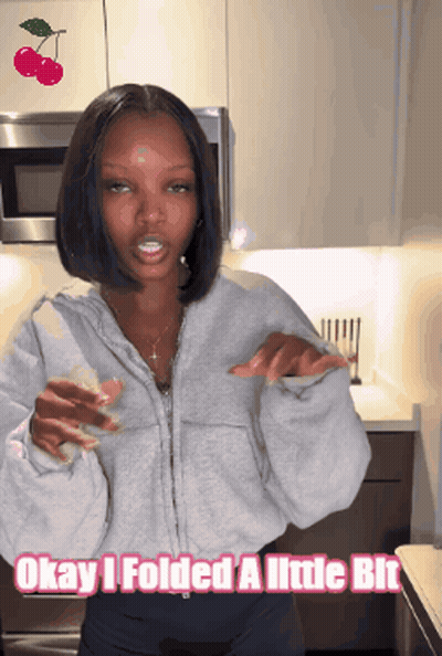 A Woman Standing In A Kitchen With The Words Okay I Folded A Little Bit Above Her GIF