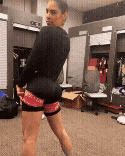A Woman Standing In A Locker Room Wearing A Pair Of Shorts That Say Steel GIF