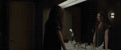 A Woman Standing In Front Of A Bathroom Mirror GIF