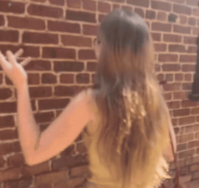A Woman Standing In Front Of A Brick Wall GIF