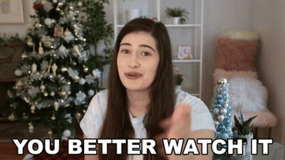 A Woman Standing In Front Of A Christmas Tree Says You Better Watch It GIF