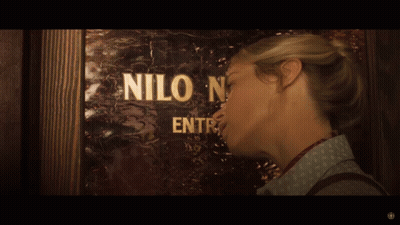 A Woman Standing In Front Of A Door That Says Nilo GIF