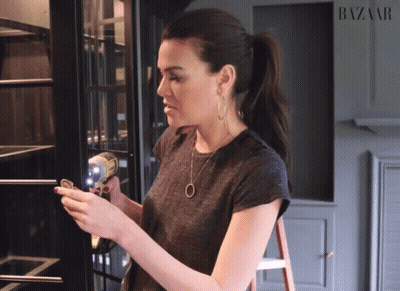 A Woman Standing In Front Of A Harper 'S Bazaar Ad GIF
