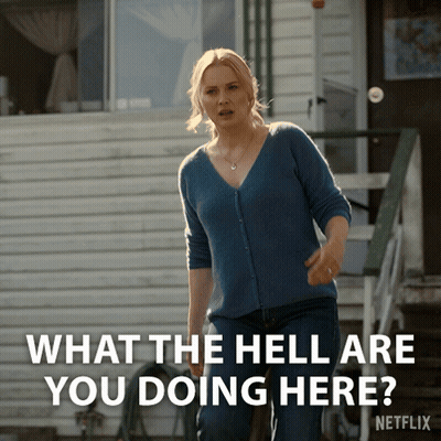 A Woman Standing In Front Of A House With The Words " What The Hell Are You Doing Here " Above Her GIF