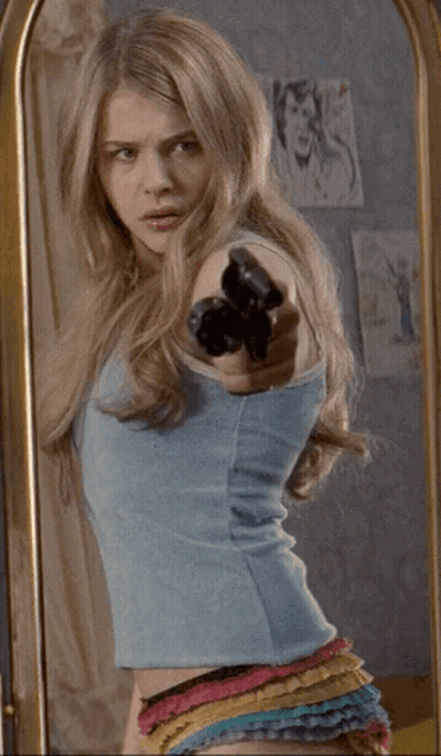 A Woman Standing In Front Of A Mirror Pointing Her Finger At Herself GIF