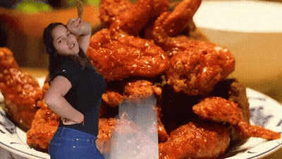 A Woman Standing In Front Of A Plate Of Fried Chicken Wings GIF