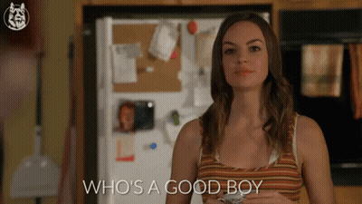 A Woman Standing In Front Of A Refrigerator With The Words Who 'S A Good Boy GIF