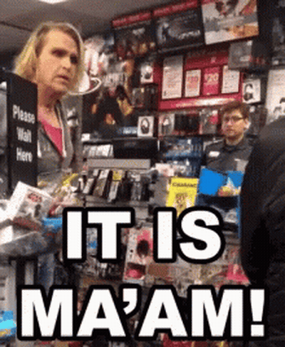 A Woman Standing In Front Of A Sign That Says It Is Ma'am GIF