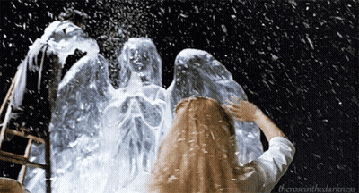 A Woman Standing In Front Of A Statue With The Words " Theroseinthedarkness " On The Bottom Right GIF