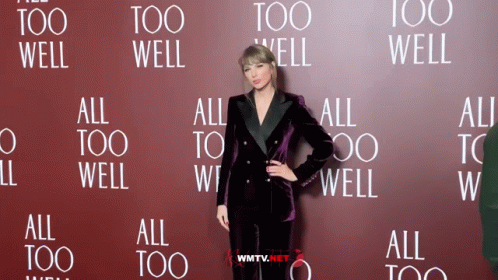 A Woman Standing In Front Of A Wall That Says All Too Well GIF