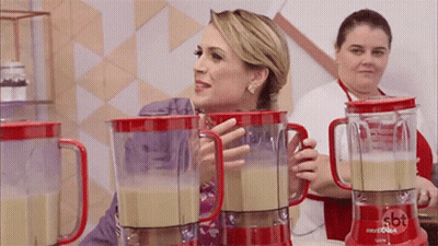 A Woman Standing Next To A Blender That Says Sbt GIF