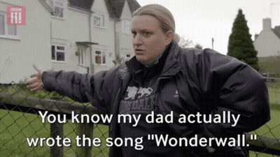 A Woman Standing Next To A Fence With The Words " You Know My Dad Actually Wrote The Song Wonderwall " GIF