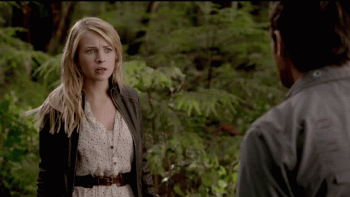 A Woman Standing Next To A Man In A Forest GIF