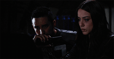 A Woman Standing Next To A Man Laying In A Bed With A Monitor Behind Them That Says A On It GIF