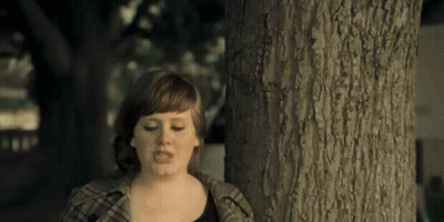 A Woman Standing Next To A Tree With A Serious Look On Her Face GIF