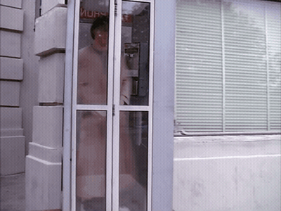 A Woman Stands In A Phone Booth With A Sign That Says ' Mura ' On It GIF