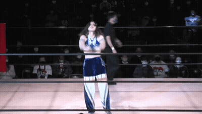 A Woman Stands In A Wrestling Ring With A Referee GIF