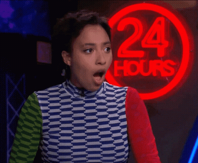 A Woman Stands In Front Of A 24 Hours Neon Sign GIF