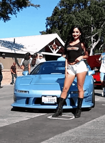 A Woman Stands In Front Of A Blue Car With A Tag That Says 1891 GIF