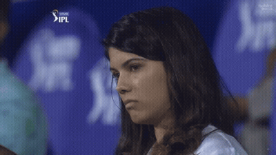 A Woman Stands In Front Of A Blue Ipl Shirt GIF
